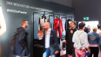 Stelen mit Designerkleidung und AEG Waschmaschinen der Serie 9000, Messebesucher