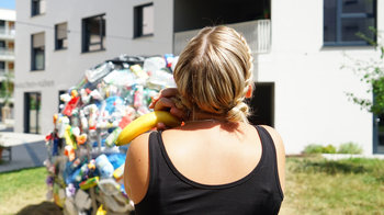Bloom-Mitarbeiterin von hinten vor Plastikabfall-Kugel