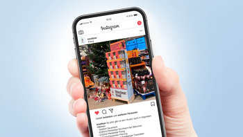 Hand hält Mobil-Telefon mit Insta-Post zu Muenchner Kindl Sonderplatzierung