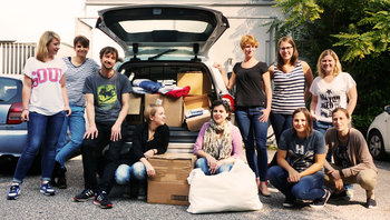 Auto mit geöffneter Heckklappe voller Spenden, Mitarbeiter